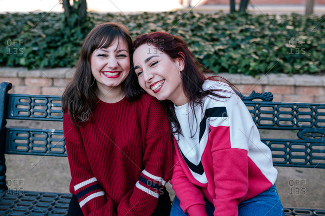 girlfriends sitting on the bench in a park