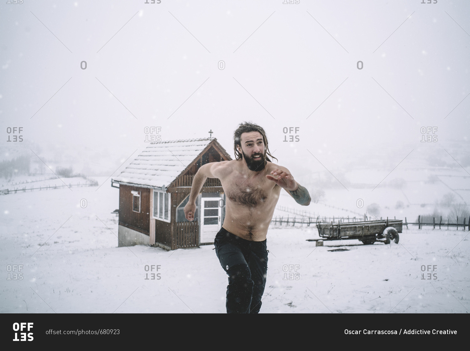 Man with a beard runs through the snow.