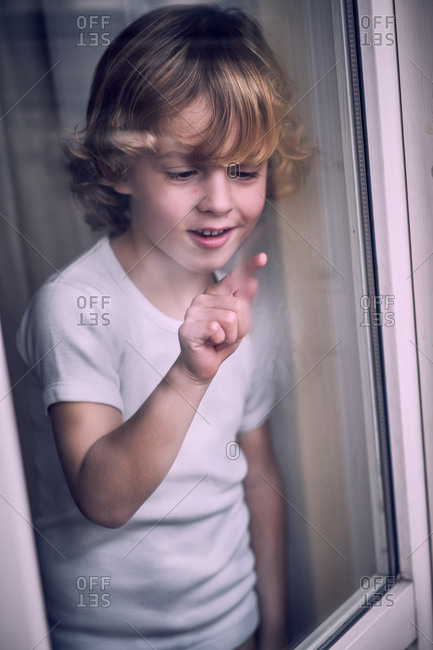 Little boy writing at window