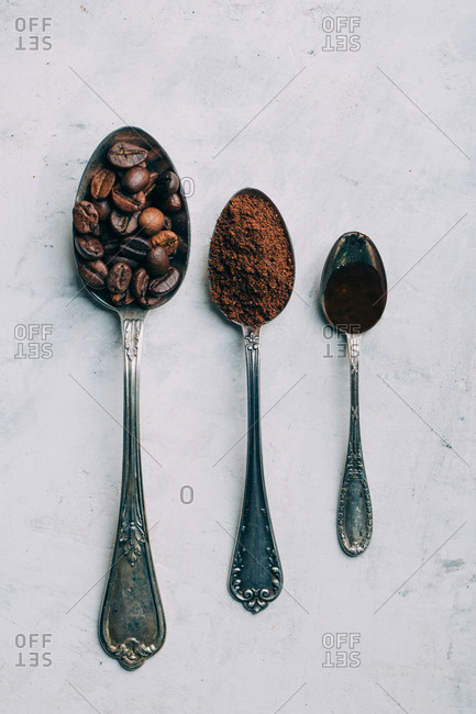 Coffee beans, ground coffee and black coffee in retro spoons