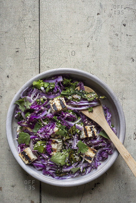Grilled tofu with red cabbage, broccoli, sesame seeds, cilantro and lime miso dressing in a bowl
