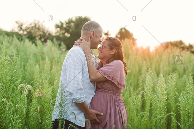 Outdoor maternity portrait of expecting mom laughing at husband