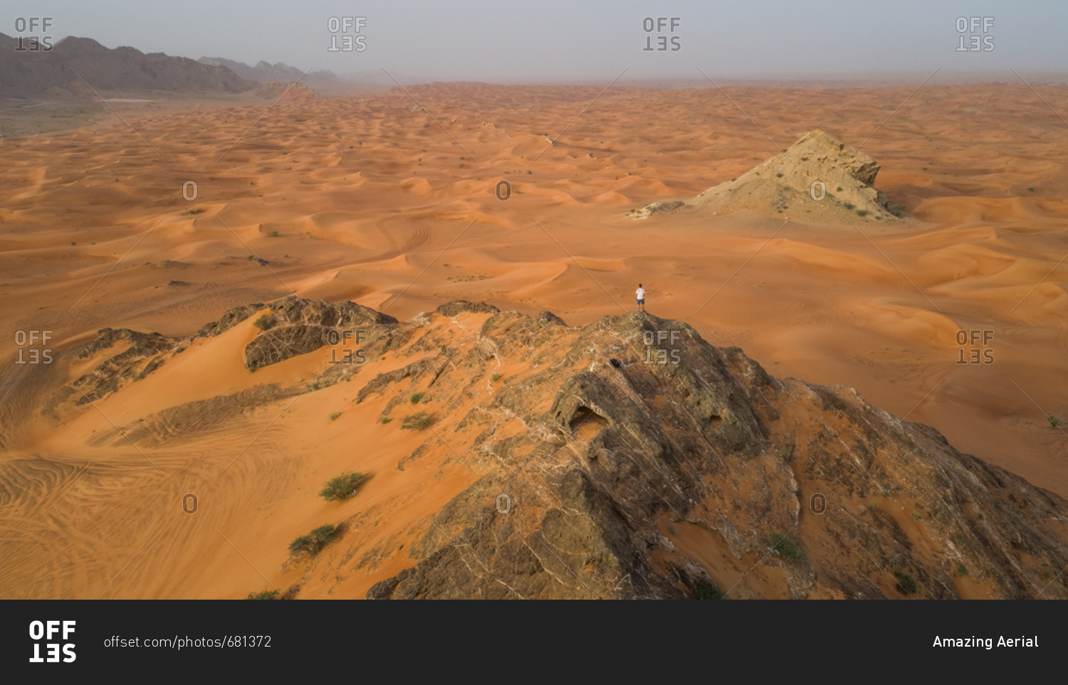 Aerial view of a man on the top of a rocky mountain in the Camel Rock Desert Safari in UAE.