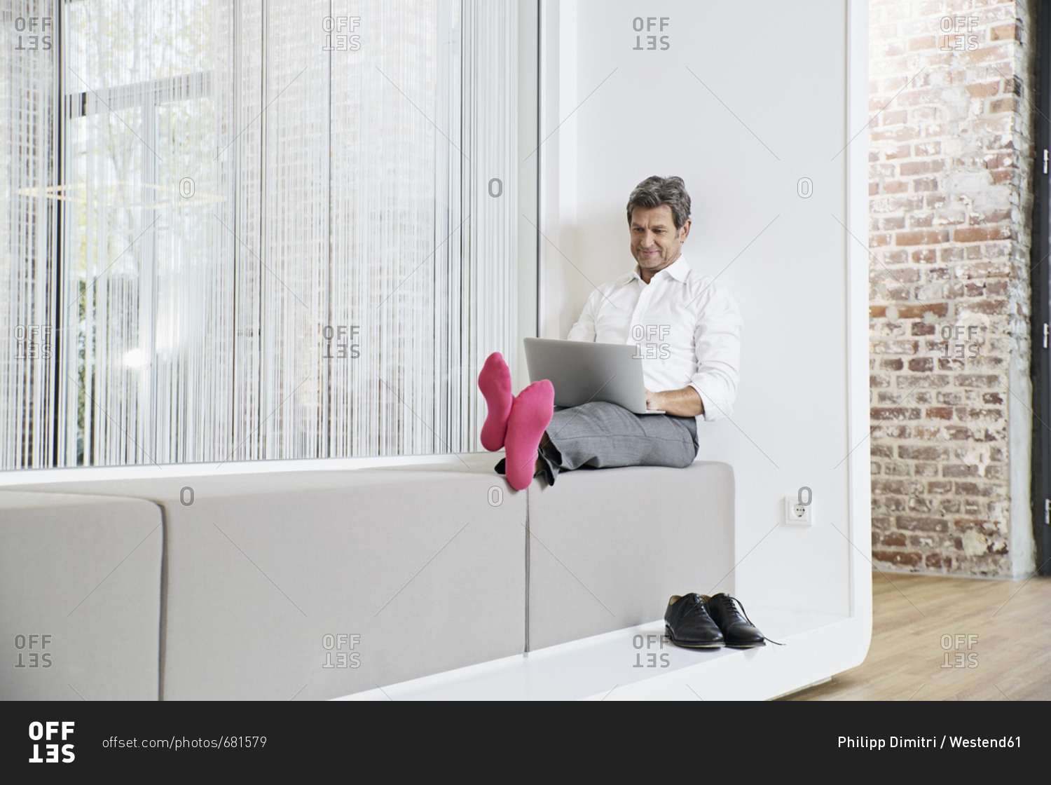 Businessman with pink socks using laptop in office