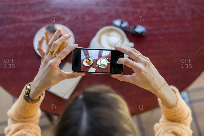 Overhead view of woman in a cafe taking cell phone picture