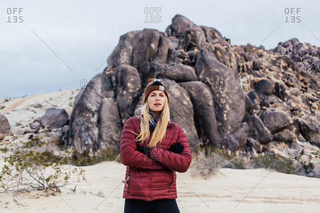 Portrait of young woman standing with arms crossed against rock formations