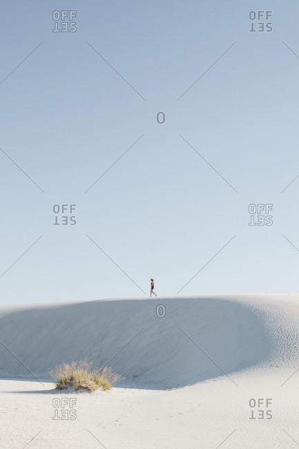 Distant view of woman walking at White Sands National Monument against clear sky