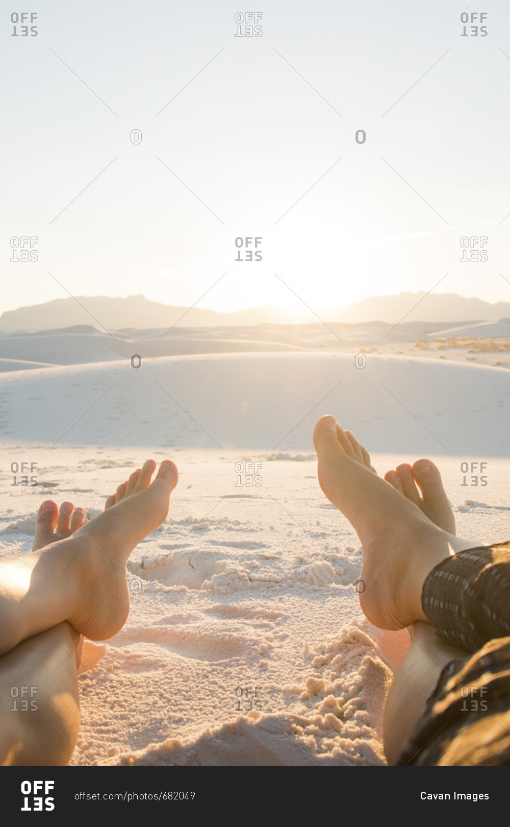 Low section of friends sitting on White Sands National Monument against clear sky during sunny day