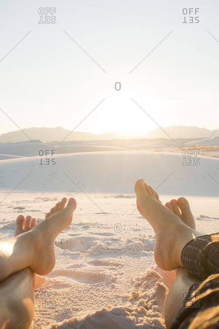 Low section of friends sitting on White Sands National Monument against clear sky during sunny day