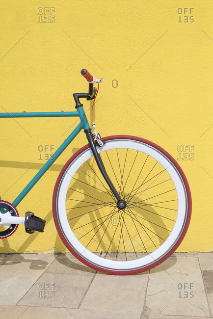 Bicycle parked against yellow wall at sidewalk in city