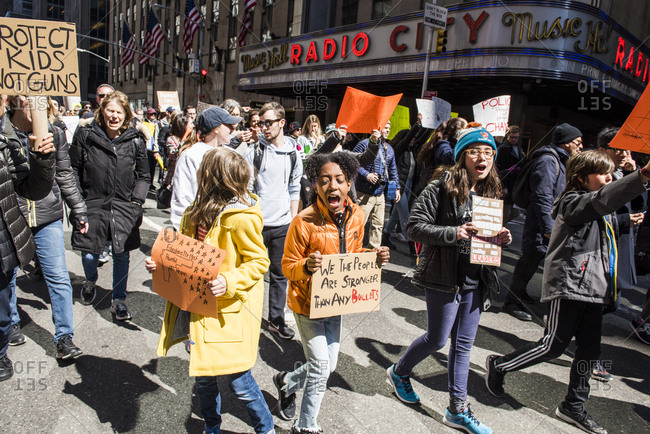 New York City, NY, USA - March 24, 2018: Group of people of all ages chanting as they walk past Radio City Music Hall during March For Our Lives 2018 demonstration