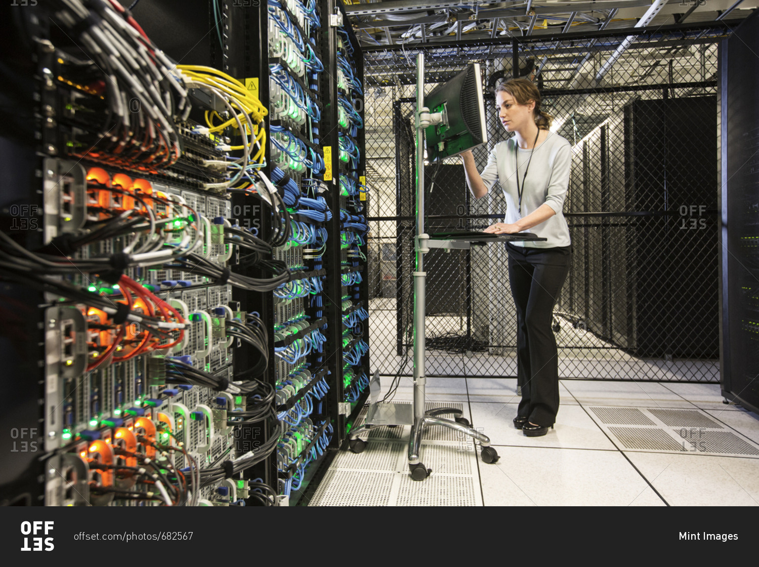 Caucasian woman technician doing diagnostic tests  on computer servers in a server farm.