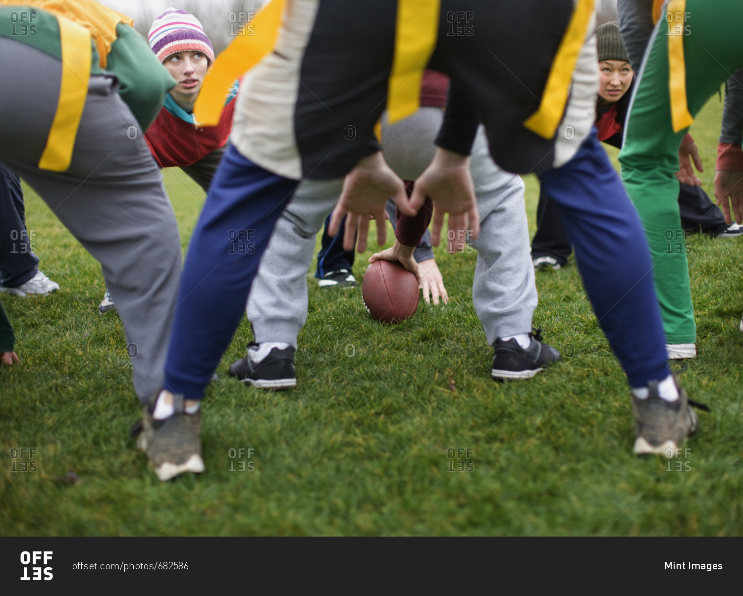 Close up of mixed team members at the line of scrimmage, playing non-contact flag football.  One player holding the ball.