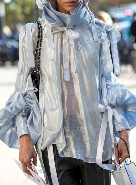 Woman wearing metallic chiffon blouse with puff sleeves and bows with leather pants