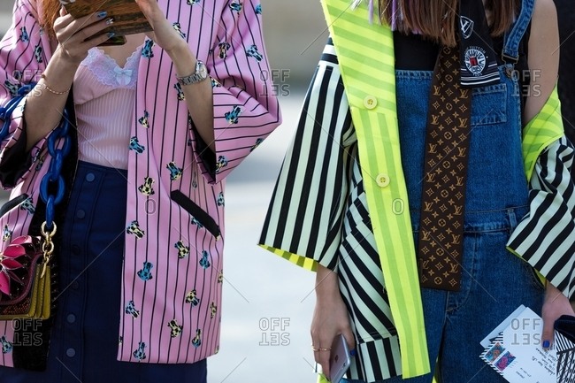 Paris, France - October 10, 2015: Pair of women wearing brightly colored striped kimono style jackets