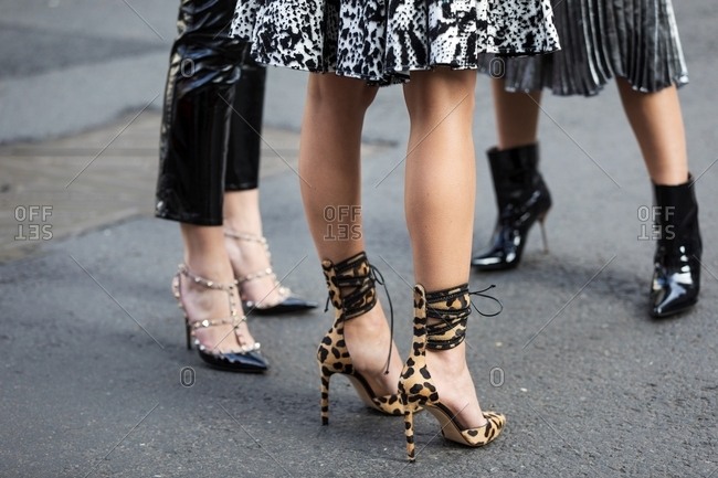 New York, USA - February 18, 2017: Trio of women wearing leopard print ankle strap heels, studded patent leather heels and patent leather ankle boots