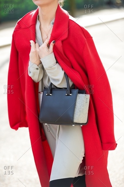 Woman holding bright red coat around her shoulders