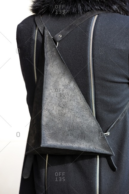 Rearview of person wearing black coat with pyramidal leather backpack