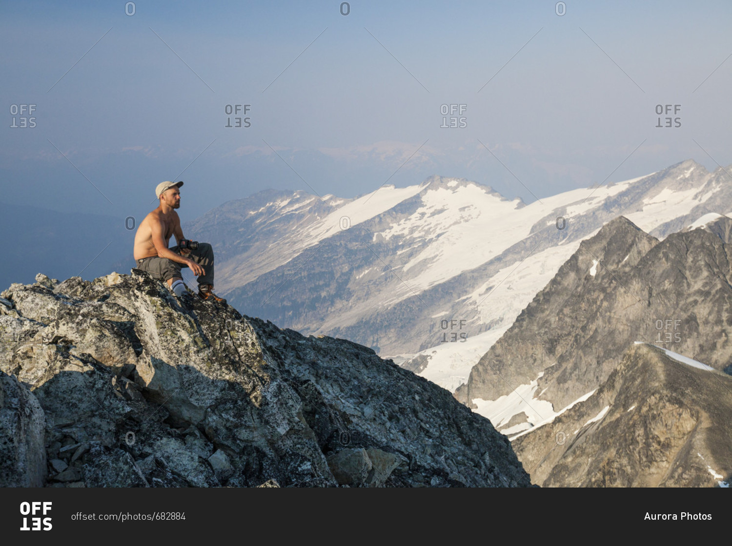 Mountain climber sitting at summit of Ashlu Mountain in Coast Mountain Range, Squamish, British Columbia, Canada