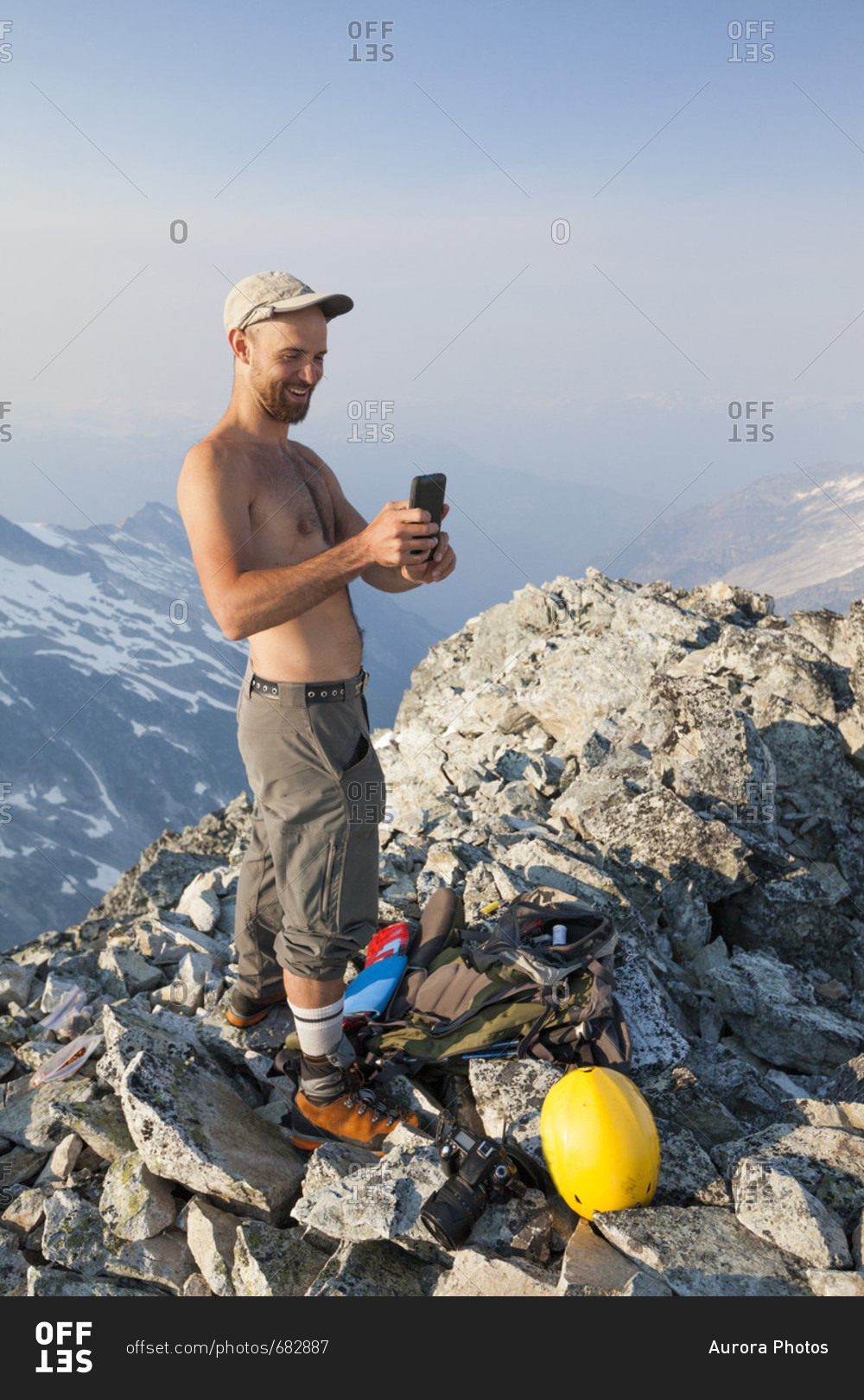 Mountain climber using smartphone at summit of Ashlu Mountain in Coast Mountain Range, Squamish, British Columbia, Canada