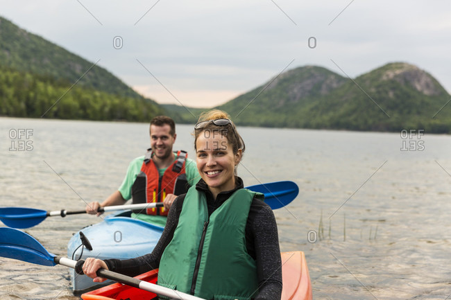 Couple smiling at camera while kayaking on Jordan Pond in Acadia National Park, Maine, USA