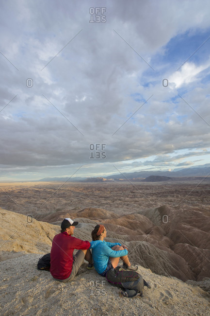 Couple sitting together in badlands section of Anza Borrego State Park and admiring landscape, California, USA