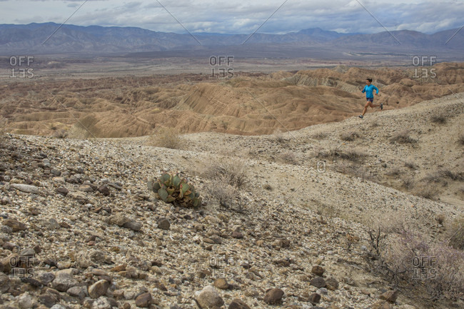 Woman running across badlands section of Anza Borrego State Park, California, USA