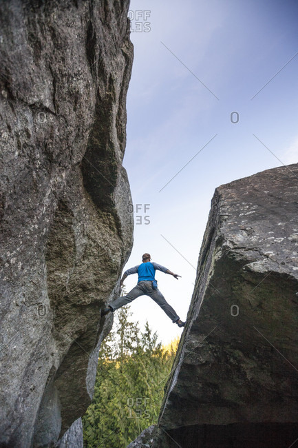 Climber bouldering between two rock faces near Elbow Lake in Fraser Valley, Harrison Mills, British Columbia, Canada
