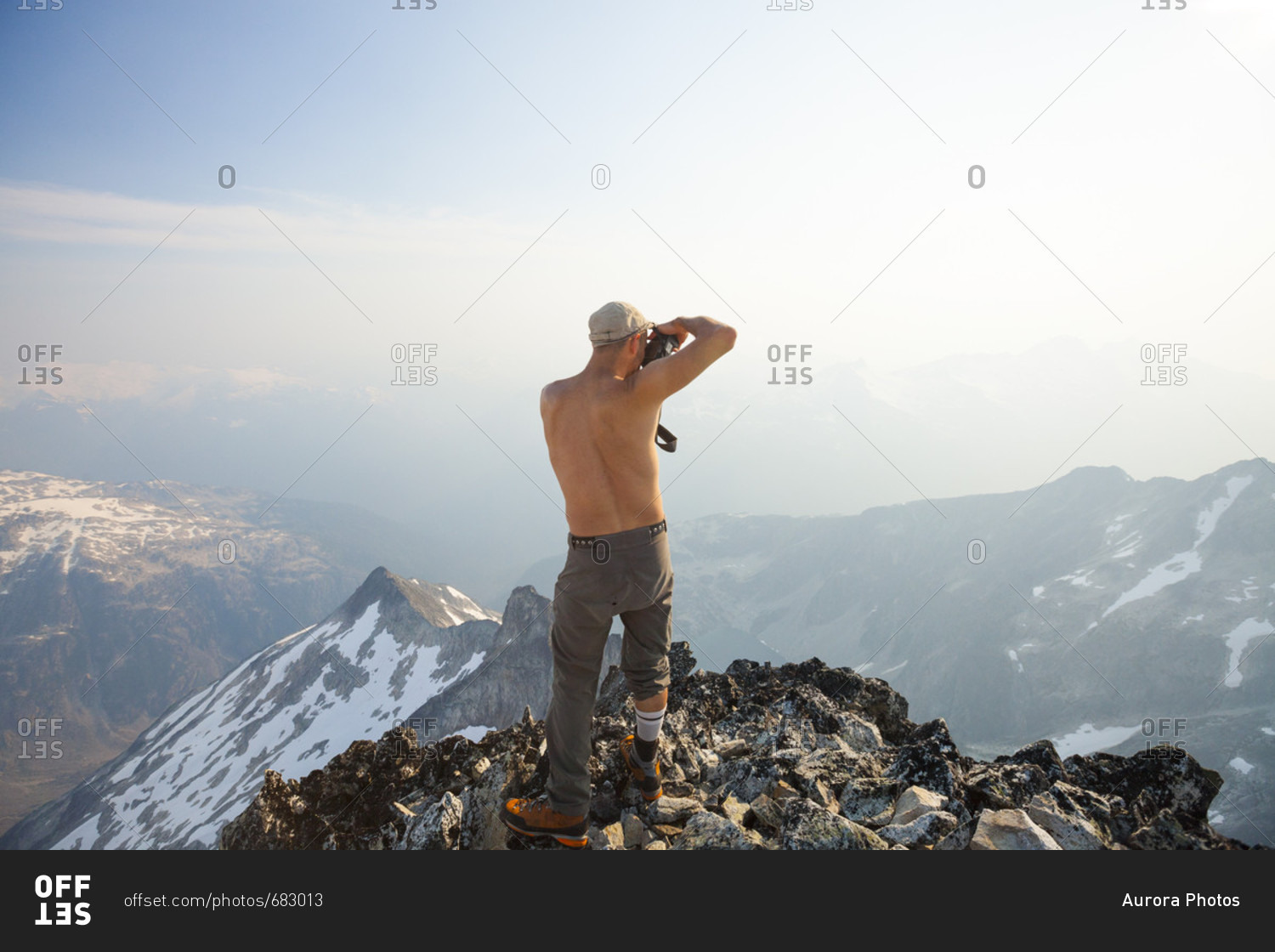 Mountain climber taking photo from summit of Ashlu Mountain in Coast Mountain Range, Squamish, British Columbia, Canada