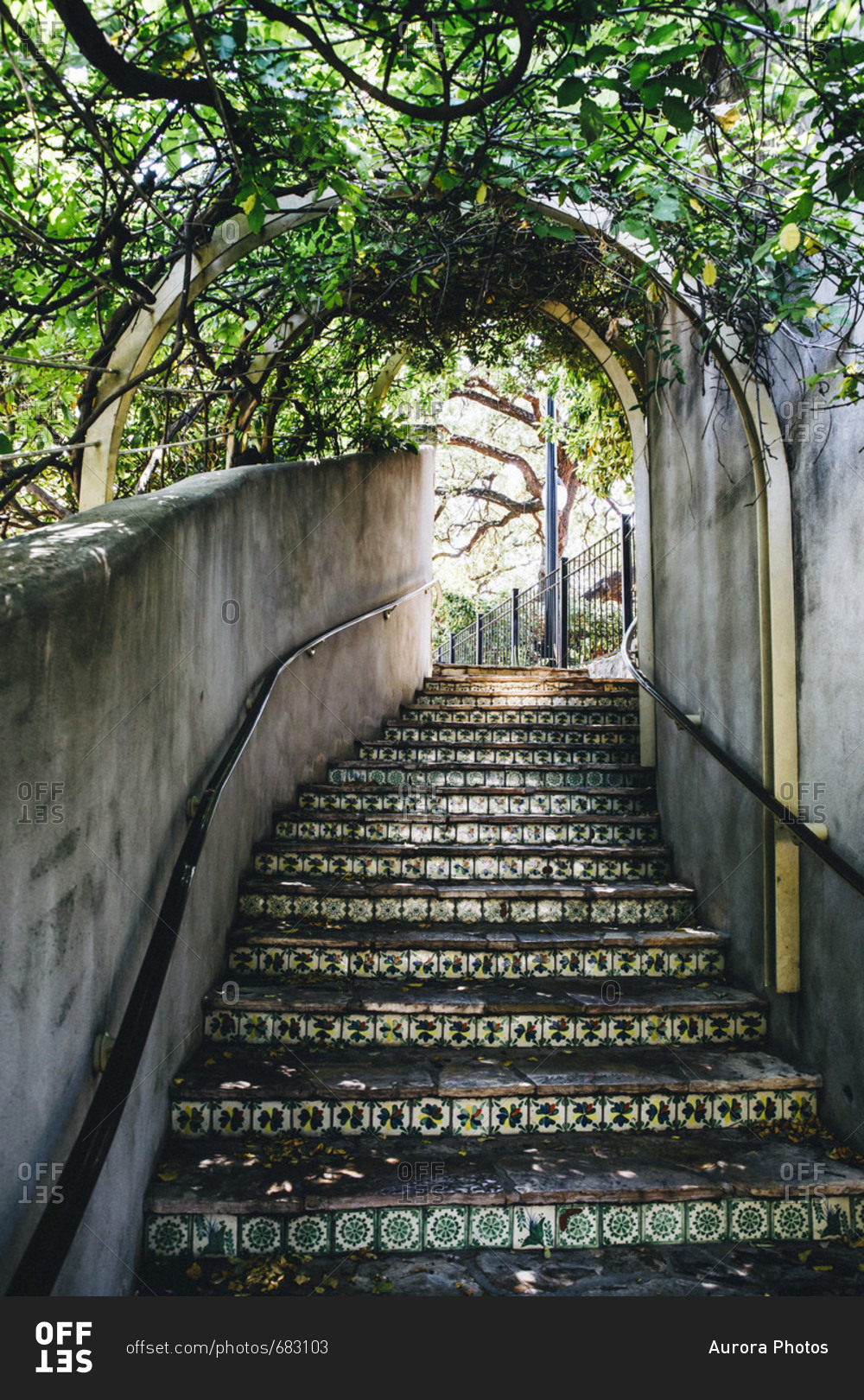Stairs lined with tile and covered with an awning of plants lead up from the San Antonio river walk to La Villita.