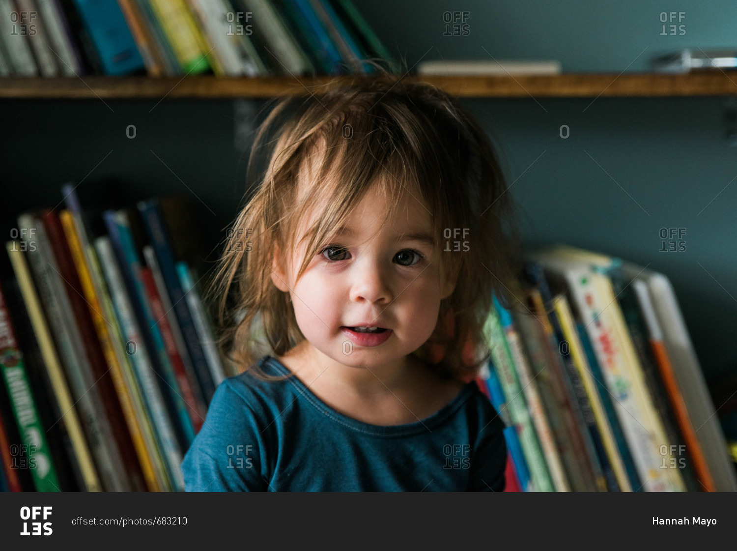 Portrait of little girl just after waking up in front of her book case