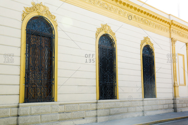 Ornate wrought iron grills covering arched windows in wall
