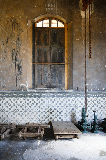 Interior of old industrial building with shuttered window and half tiled wall