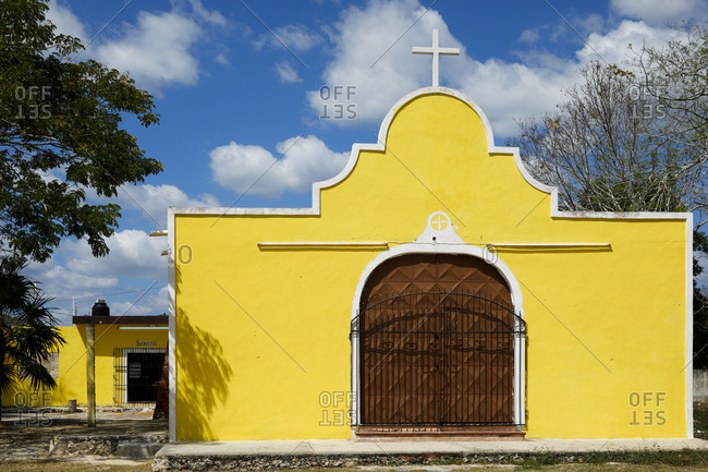 Exterior view of small church painted yellow with white border