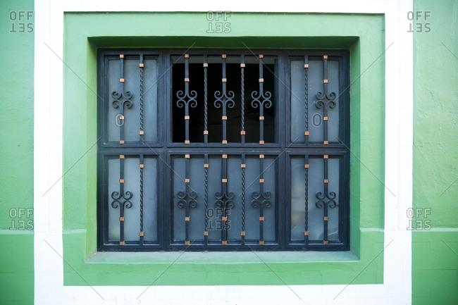 Ornate iron grill covering window in green wall in Valladolid, Mexico