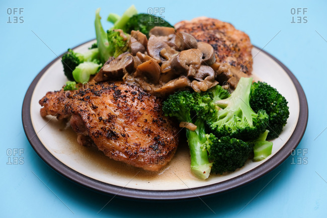 pieces of appetizing roasted chicken and broccoli on blue table.