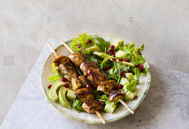 Salad with skewers of chicken breast with avocadoes and pomegranates