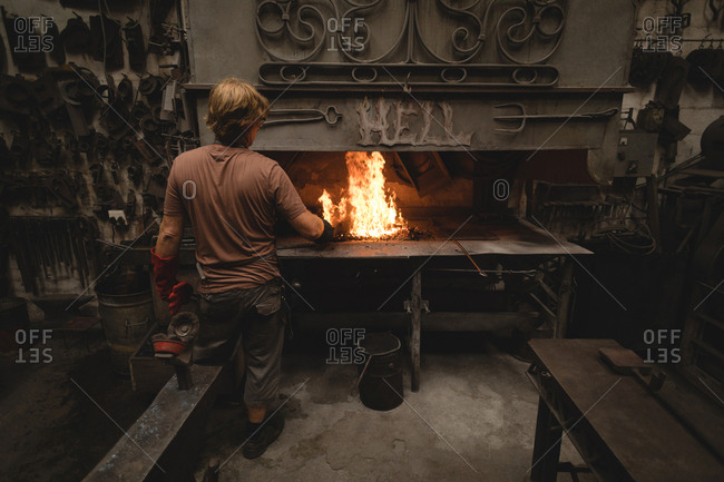 Blacksmith heating metal rod in fire
