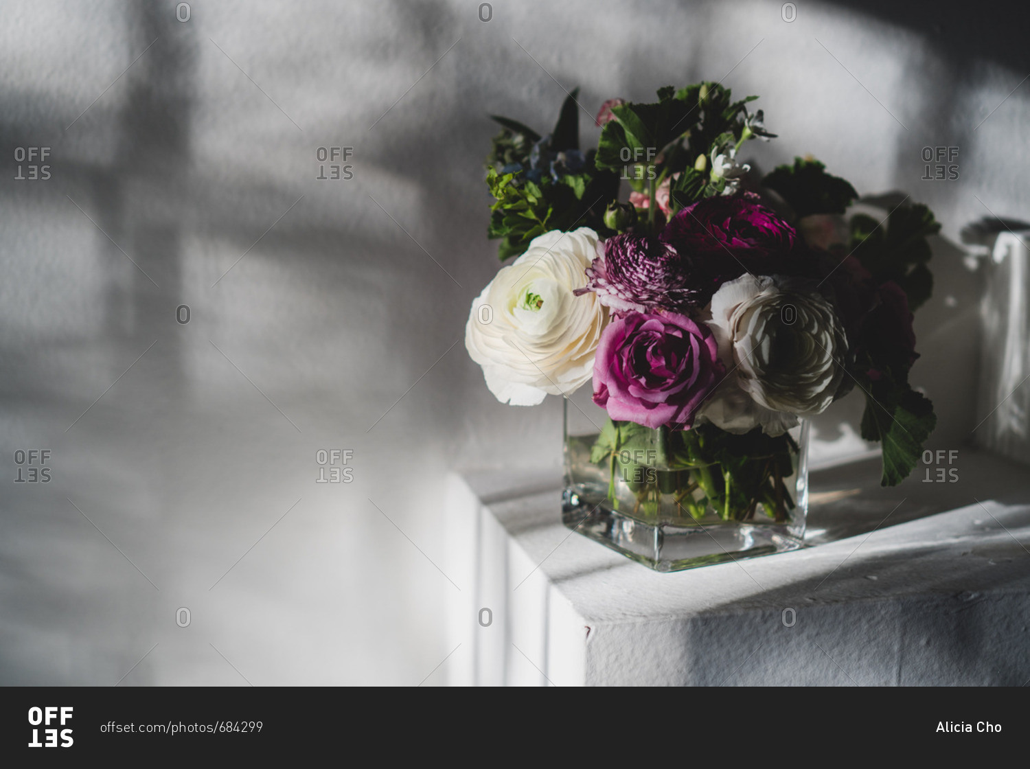 Purple and white flowers arranged in a square glass vase