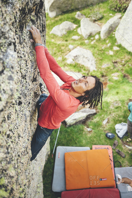 Hoya Moros, Spain - July 2, 2011: Rock climber climbing a granite boulder problem with crash pads below
