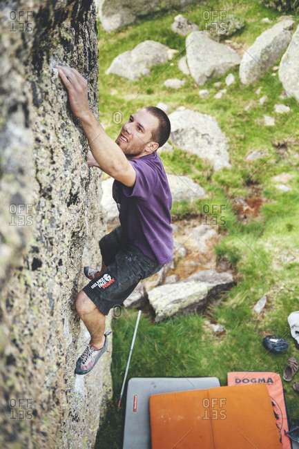 Hoya Moros, Spain - July 2, 2011: Rock climber climbing a granite boulder with crash pads below