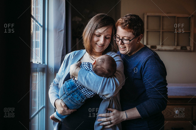 Smiling same sex couple holding new baby