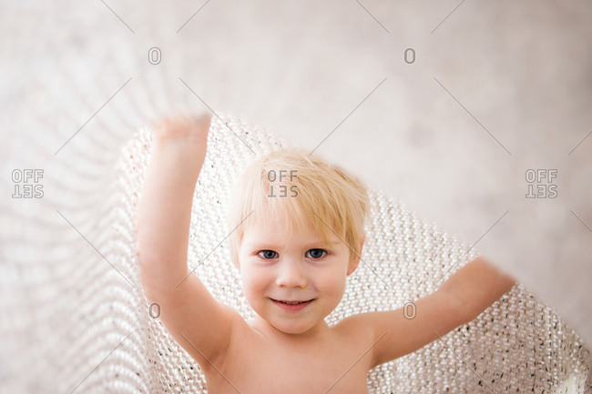 Playful toddler lifting textured blanket over head