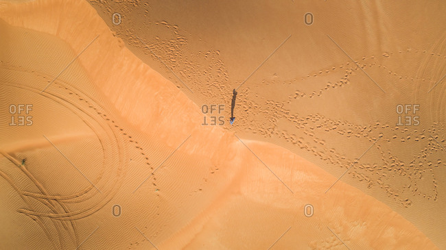 Aerial view of a man walking alone in the dunes of Sharjah desert, UAE
