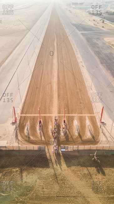 Aerial view of jockeys and camels on racetrack in Dubai, UAE