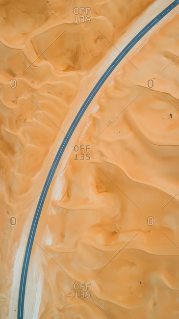 Aerial view of an empty curved road in the desert of Abu Dhabi, UAE