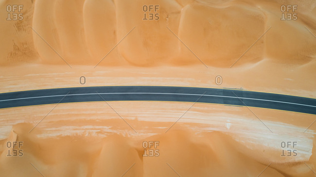 Aerial view of an empty curved road in the desert of Abu Dhabi, UAE