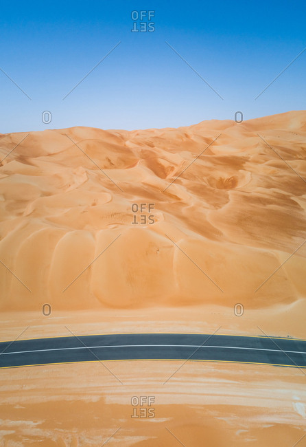 Aerial view of an empty curved road in the desert of Abu Dhabi, UAE