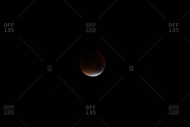 The majority of the moon in shadow with just the edge highlighted during a full lunar eclipse