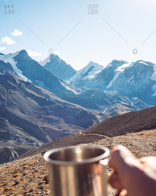 Person holding cup in front of scenic mountain view